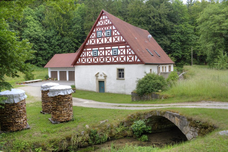 Schwarzmühle im Kleinziegenfelder Tal mit dem Flusslauf der Weismain und einer historischen Steinbrücke