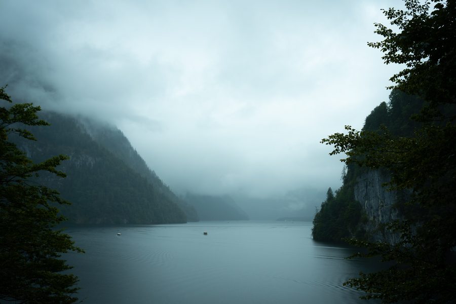 Blick vom Malerwinkl auf den Königssee mit bewaldeten Bergen und Booten im Nebel